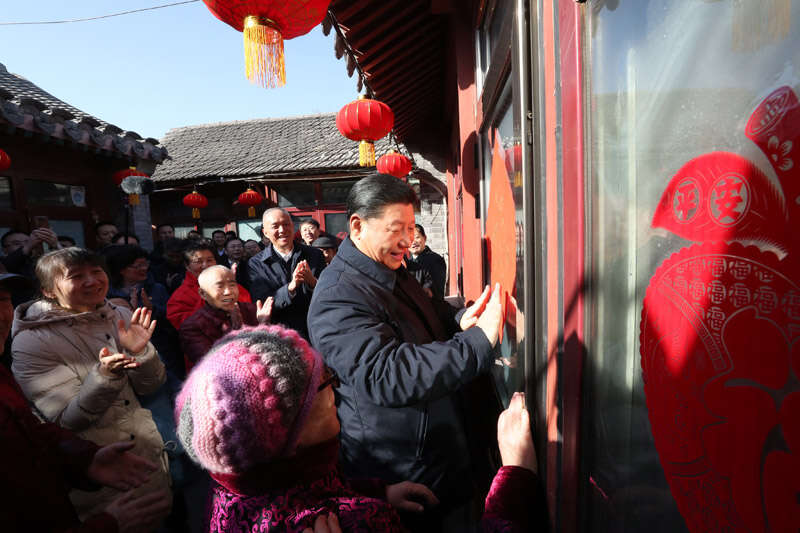 2019年2月1日上午，習近平在北京前門東區(qū)草廠四條胡同32號院，高興地拿起一幅“?！弊郑H自貼到門上，給這里的老街坊們拜年。新華社記者 鞠鵬 攝